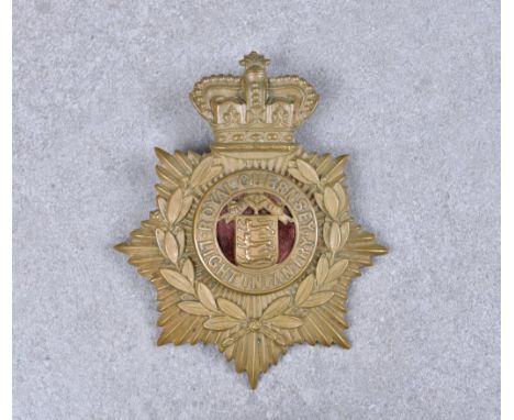A Royal Guernsey Light Infantry brass helmet plate, bearing Crown, laurel and centred by insignia on maroon cloth backing, 5¼