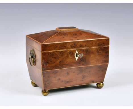 A George III burr yew tea caddy, of sarcophagus form with string banding, loose ring handles to brass flower basket mounts, t