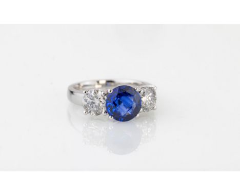 An 18ct white gold, sapphire and diamond three stone ring, the round cut 2.20ct sapphire of fine colour, flanked by two brill