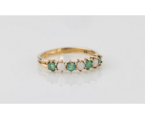 A 9ct yellow gold, opal and emerald seven stone ring, the four round cut emeralds spaced with three round cabochon opals, on 