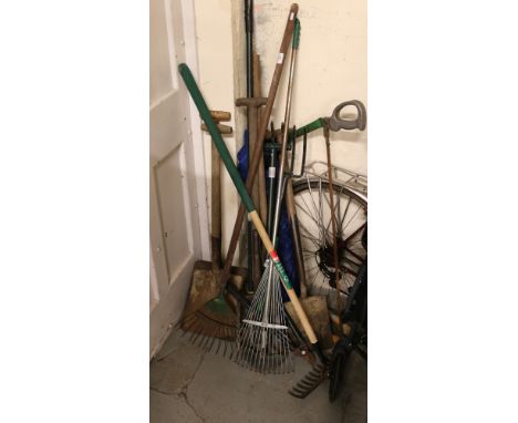 A collection of garden tools to include rakes, shovels, saw, pitch fork etc.