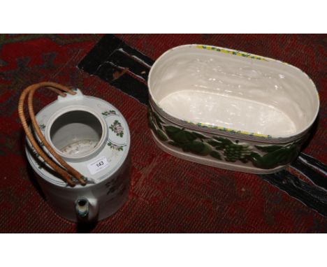 A ceramic bread bin decorated with leaves, along with a large ceramic teapot.