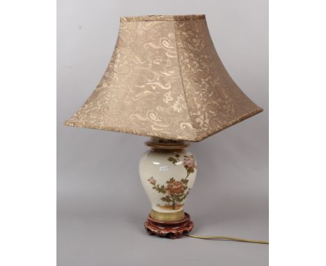 A Japanese style baluster shape table lamp with floral decoration on hardwood stand.