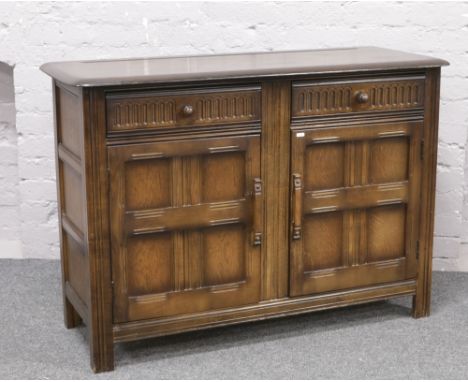 An Ercol carved and panelled dark oak sideboard. H 86cm L 121cm D 46.5cm.