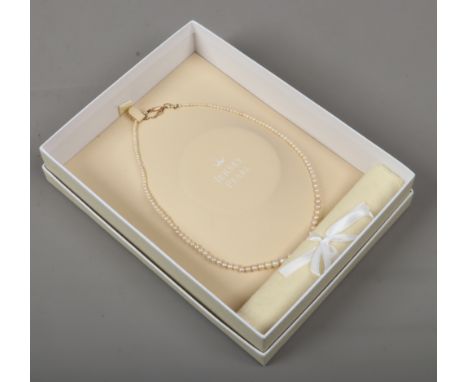 A boxed string of graduated pearls with 9ct gold clasp and safety chain.