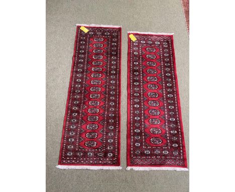 Two Pakistan Bokhara handknotted wool red ground rugs, with central panel of lozenge patterns, and stylized borders.&nbsp; 17