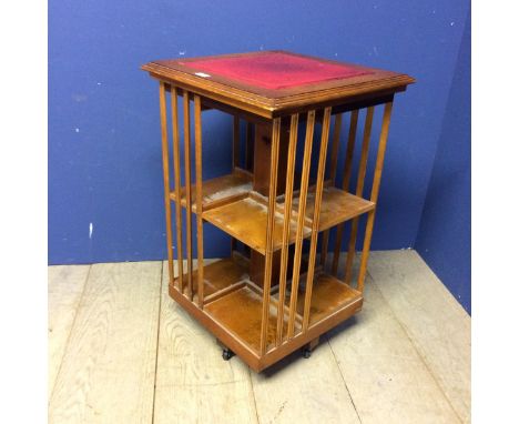 Small revolving light wood pedestal book case with red inset top 78h x 48 x 48cm 