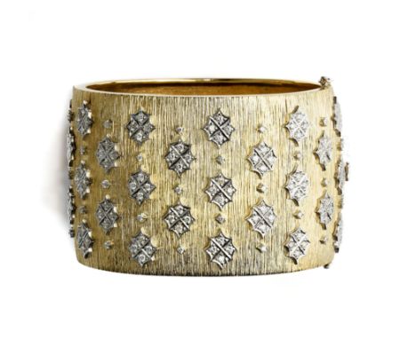 DIAMOND BANGLE, 1960s designed as a wide textured hinged cuff, applied with stylised holly leaves set with brilliant-cut diam