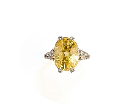 YELLOW SAPPHIRE AND DIAMOND RING centring on an oval mixed-cut yellow sapphire, to an openwork mount accented with millegrain