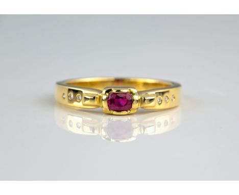 An 18ct yellow gold, ruby and diamond ring, the oval cut ruby over in an oblong four claw setting over shoulders inset with s