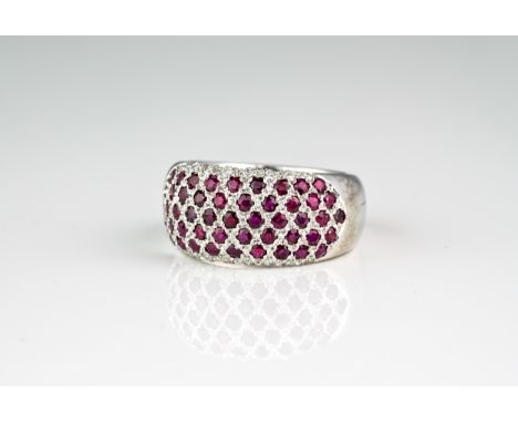 An 18ct white gold, ruby and diamond dress ring, the domed ring pavé set with round cut rubies, bordered to either side with 