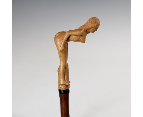 A novelty erotic walking stick, late 20th century, probably Philippines, the slender malacca cane terminating in a carved woo