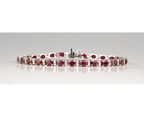 An 18ct white gold, ruby and diamond line bracelet, the twenty six oval cut rubies, total 10.80cts,divided by pairs of brilli