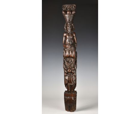 A 17th century carved oak caryatid panel, modelled as a bearded male figure with bare torso and lower robes, a basket of frui