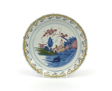 A Brislington delftware plate  c.1710-20, painted in polychrome enamels with a hut beneath a pine tree and other tall bushes,