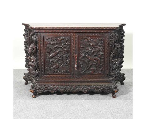 An early 20th century Chinese heavily carved side cabinet, mid 20th century, profusely carved throughout with dragons and enc