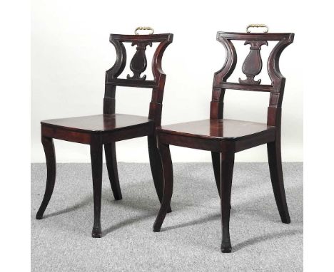 A pair of Regency mahogany hall chairs, each with an hourglass back and solid seat, on sabre legsBoth are solid, usable and l