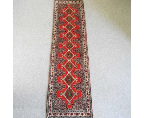 A Persian runner, with a row of central medallions, within an ivory border, 310 x 85cm