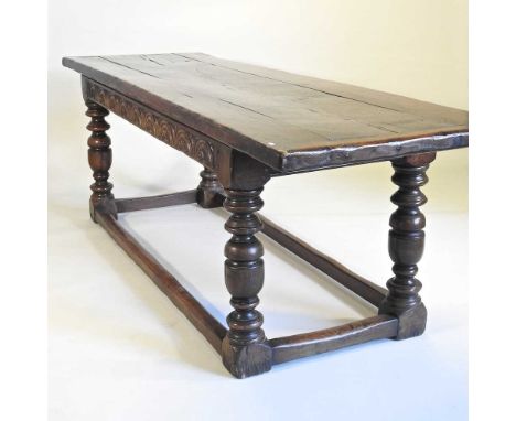 A 17th century style oak refectory table, 19th century elements, with a plank top and carved frieze, on turned legs, united b