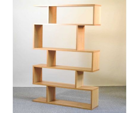 A modern light oak open bookcase, of asymmetric design120w x 30d x 179h cm