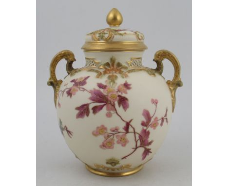 A Royal Worcester spherical glided ivory two handled covered vase, with pierced neck and decorated with flowers, height 8.25i