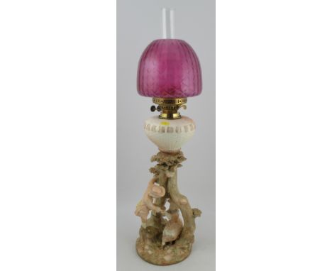 A Royal Worcester blush ivory oil lamp, modelled with Kate Greenaway figures, shape No. 1240, with associated pink glass shad