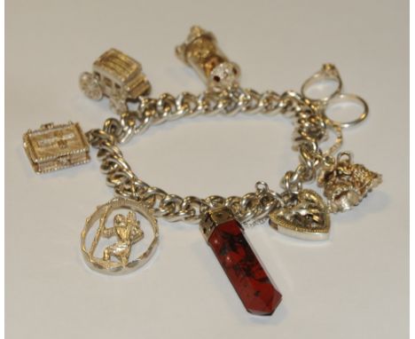 A silver charm bracelet, the curb-link chain with various charms, miniature clock, carriage, St Christopher, etc