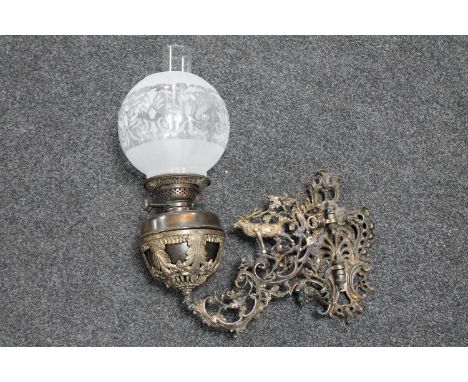 A Victorian cast patinated wall bracket with oil lamp and glass shade 