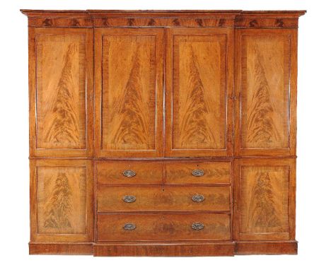 A George III mahogany breakfront clothes press, circa 1800, the moulded cornice and frieze above a central pair of panelled d