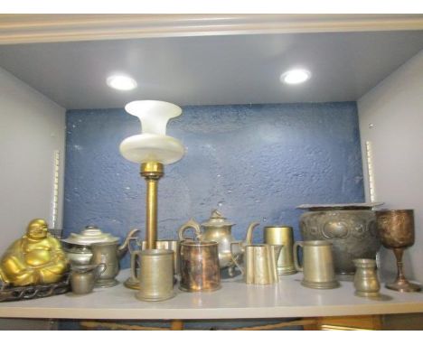 A quantity of mixed metalware to include a brass lamp with a frosted glass shade, Victorian and later mugs, a brass Buddha on