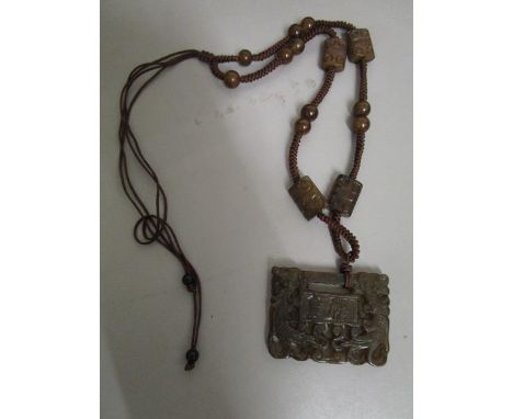 A Chinese carved jade pendant plaque, rectangular shaped on a woven cord necklace with carved jade beads and brown stone spac