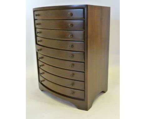 A Hardwood Bow Fronted Collectors' Chest of nine drawers with knob handles raised upon bracket feet, 41 cms tall