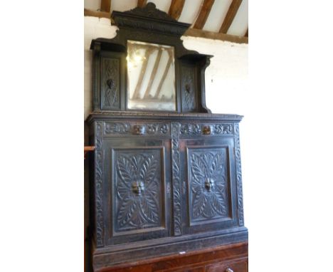 A Victorian Carved Oak Chiffonier, the mirrored shelf back with carved mask heads above two similar frieze drawers and two cu