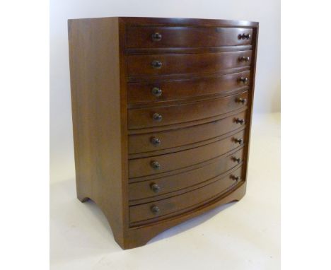 A Hardwood Bow Fronted Collectors' Chest of eight drawers with knob handles raised upon bracket feet, 49 cms high