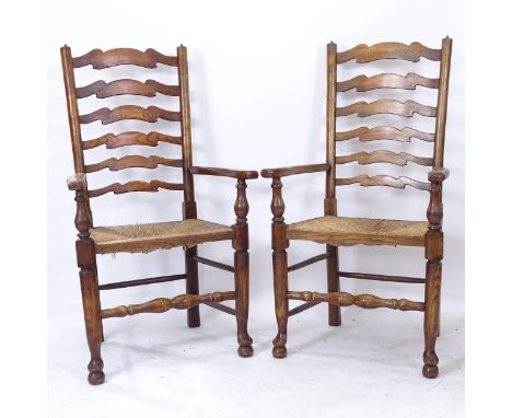A pair of oak and elm ladder-back elbow chairs, with rush seats 