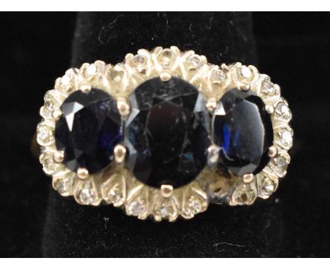 An 18ct yellow gold sapphire and diamond lady's dress ring, set with three large sapphires and surrounded by twenty-five smal