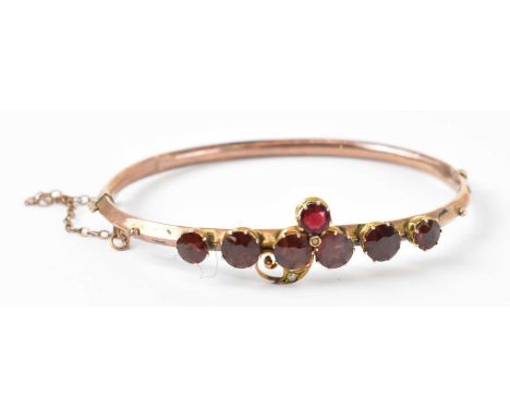 A 9ct yellow gold Edwardian bangle set with seven garnets,diameter 6.5cm, approx 5.7g.
