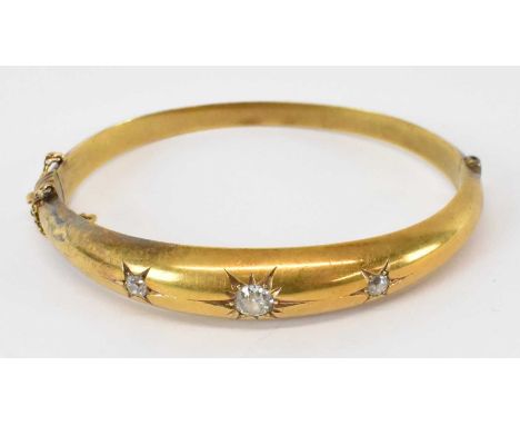 A yellow metal bangle set with three large white stones, approx 13.2g, boxed.