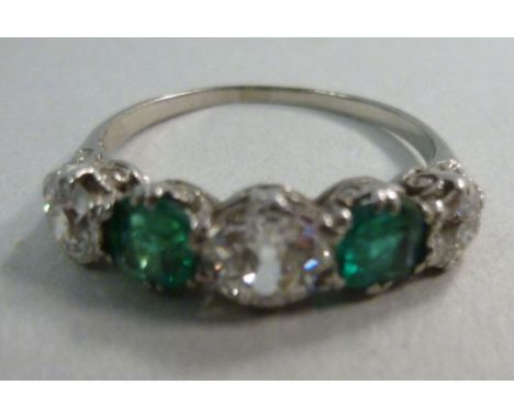 A white metal, five stone ring, set with alternating green stones and diamonds