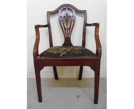 A George III mahogany framed elbow chair, having a carved, serpentine outlined crest, a ribbon and rosette, pierced splat, th