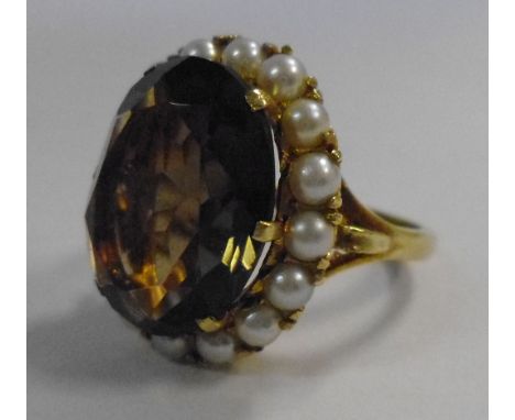 A gold coloured metal ring, the oval quartz surrounded by seed pearls