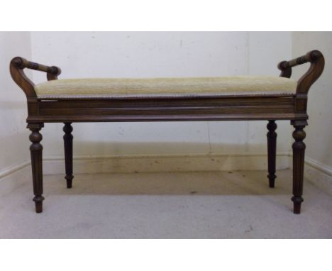 A late Victorian mahogany framed duet stool, having opposing twin ring turned handles and a hinged, beige dralon upholstered 