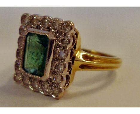 A gold coloured metal, square set emerald ring, surrounded by diamonds 