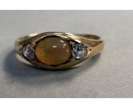 An 18ct gold ring, set with a central cabochon cut opal, flanked by two diamonds   