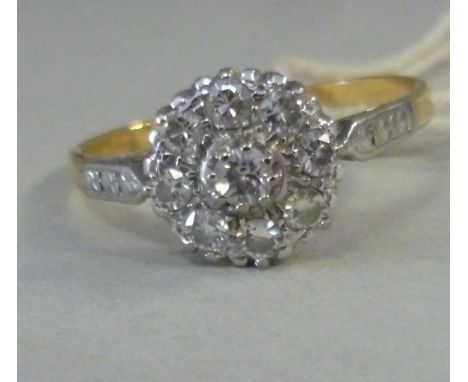 A yellow metal nine stone diamond cluster ring