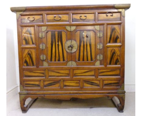 A late 19thC Korean exotic hardwood cabinet, having a recessed panelled top, over four in-line drawers and twin panelled door