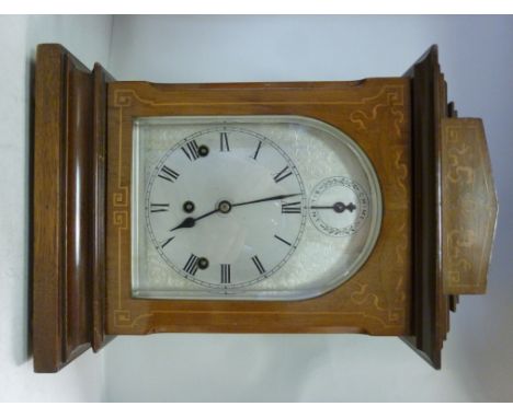 An Edwardian string inlaid mahogany and marquetry cased bracket clock, having a stepped top, over a glazed door, on a moulded