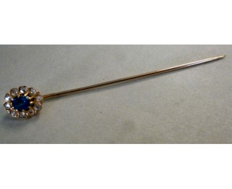 A gold coloured metal stickpin, the head set with a sapphire, surrounded by diamonds