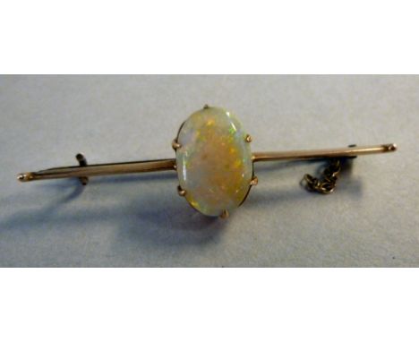 A gold coloured metal bar brooch, set with a single, oval opal