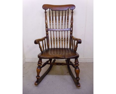 A late 19thC elm and fruitwood framed rocking chair, having a ring turned spindle back, scrolled arms and a solid seat, raise